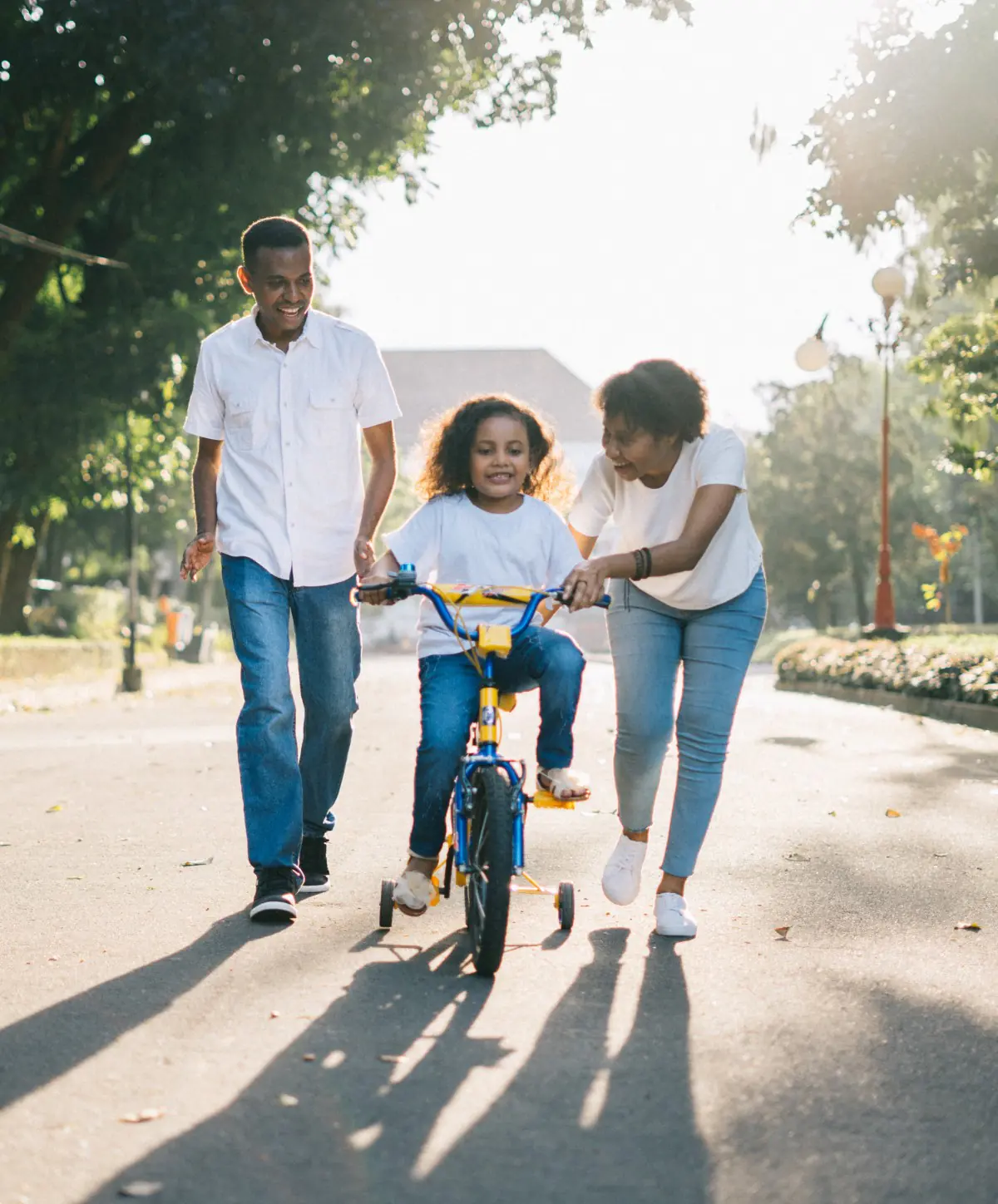 African Canadian parents teach their daughter how to ride a bike on a quiet residential street